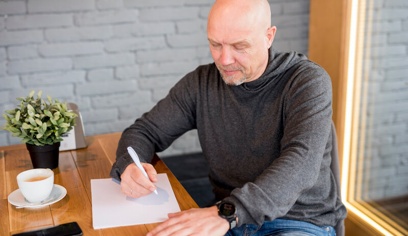 homme qui rédige sa lettre de démission à la main
